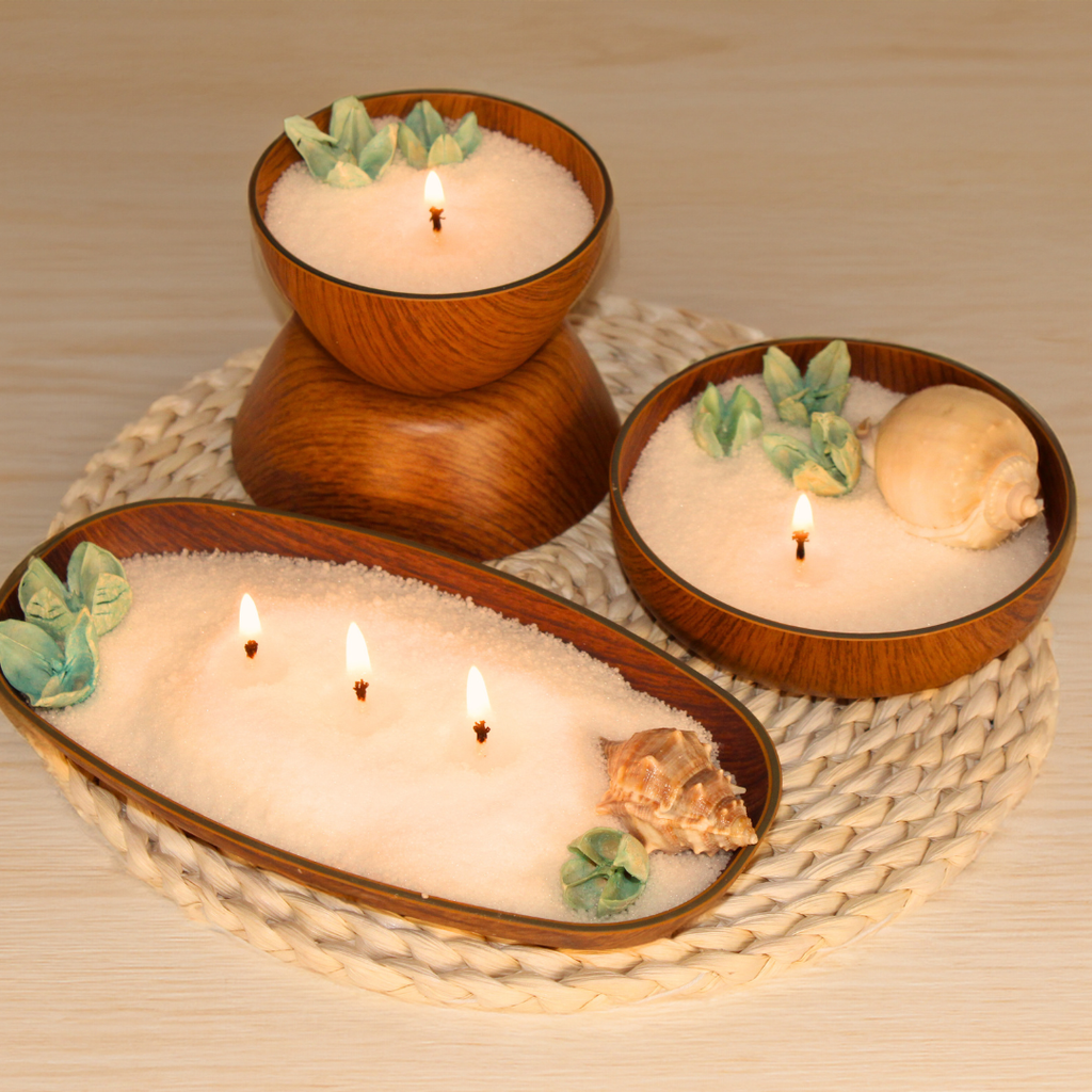 Ivory pearled candle wax in wooden bowls with lit wicks and shells