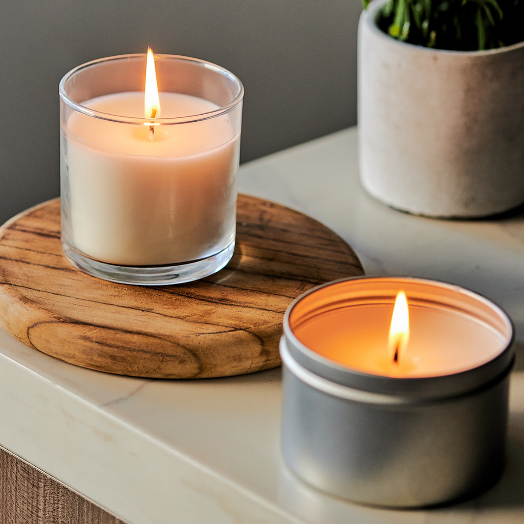 Lit candles in a glass jar and a silver tin