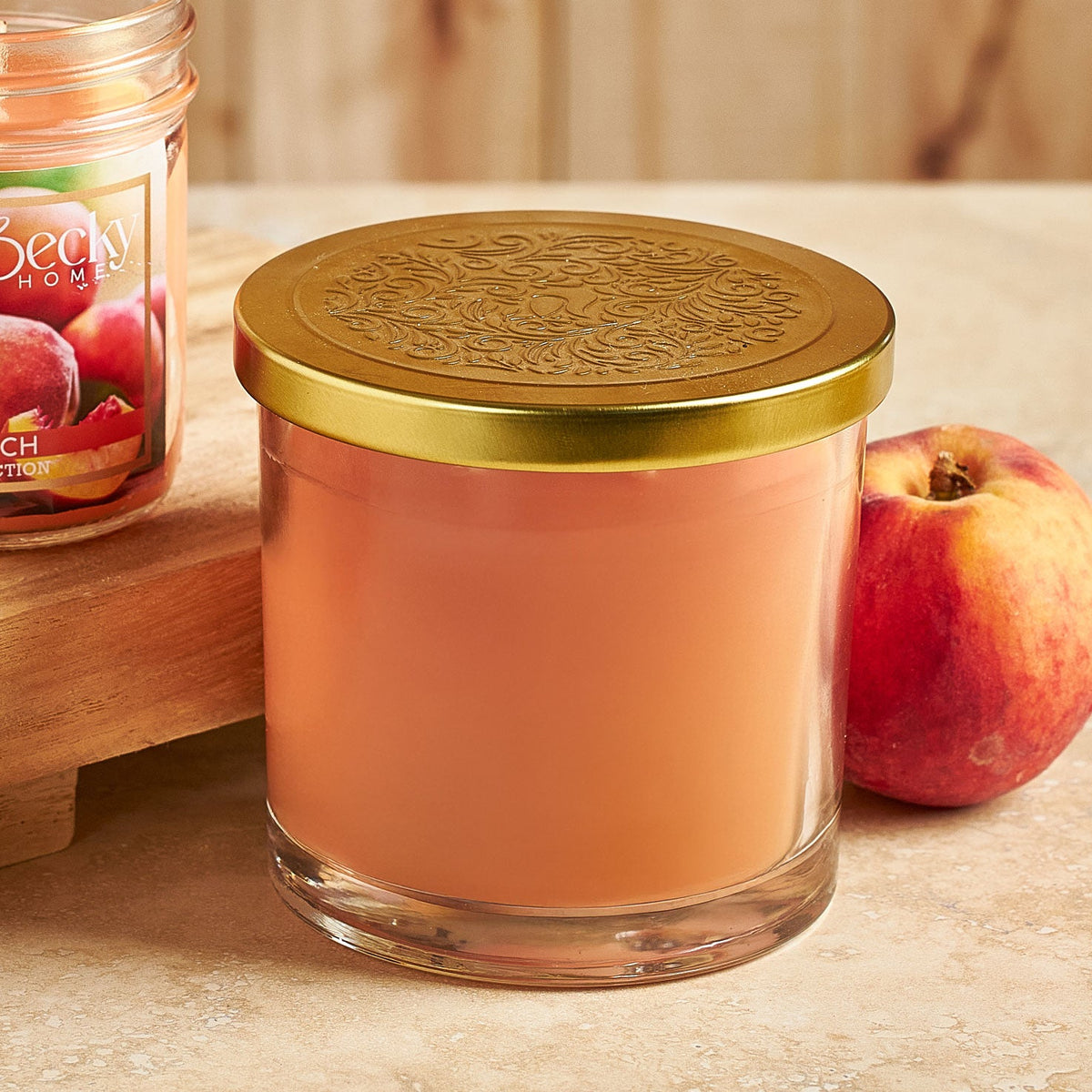Peach-colored candle in a glass jar with a 14.5 oz gold lid