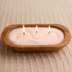 Wooden bowl candle made with pink pearled candle wax and three lit wicks