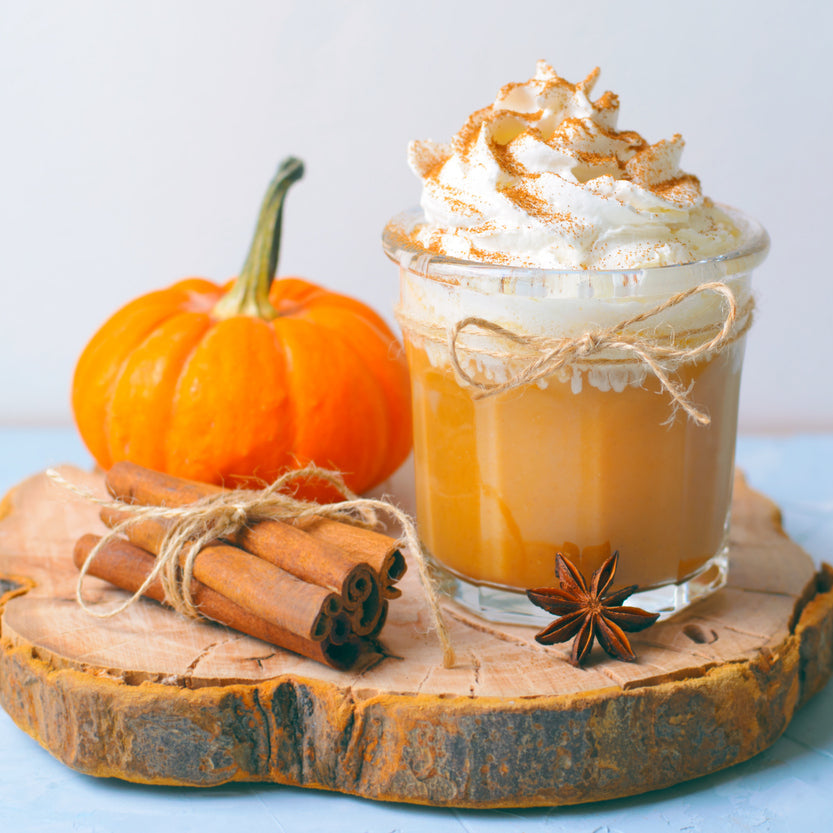 Pumpkin spice latte with whipped cream, a small pumpkin, and cinnamon