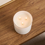 Lit three-wick candle in a 14.5 oz white glass jar on a wooden shelf